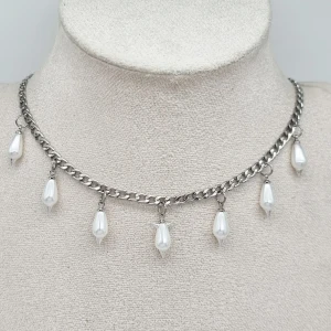 Silverhalsband med droppformade pärlor - Kedjehalsband i silverfärg med sju hängande droppformade vita pärlor. Rostfrit stål, glaspärlor. Längd-40cm,kedjetjocklek-4cm 