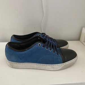 Blå mocka sneakers från Lanvin - Stilrena sneakers från Lanvin i blå mocka och glans på captoen.  Tyvärr ingår inte box och dustbag. Det är bara att skriva om du har frågor eller vill ha fler bilder! Det är storlek 8 vilket är 42 men Lanvins är stora i storleken och passar dem som har 43