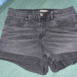 Svarta jeansshorts från H&M - Snygga svarta jeansshorts från H&M i klassisk femficksmodell. De har uppvikta benslut, normal passform och midwaist. Perfekta till sommaren och lätta att matcha med allt. Materialet är stretchigt jeans för extra komfort.