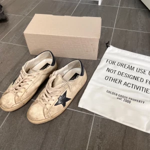 Golden Goose Superstar sneakers beige/svart - Golden Goose Superstar skor, de är lite skadade i hälen men inget man tänker på, medföljer original box och dustbag. Köpta på merchsweden. Kvitto finns.