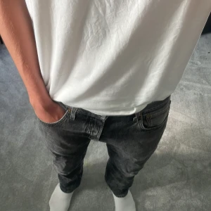 Levi's 501 svarta jeans straight fit - Svarta Levi's 501 jeans med klassisk rak passform och femficksdesign. Jeansen har en snygg tvättad look och är tillverkade i robust denim. Perfekta för dig som gillar en avslappnad stil med tidlös känsla. Lite slitningar längst ner på höger ben. 