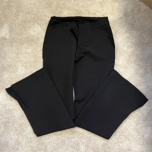 Svarta bootcut kostymbyxor BikBok - Snygga svarta kostymbyxor från BikBok i storlek 36. Byxorna har bootcut-modell med vida ben och klassisk midja. Det är en slits också.