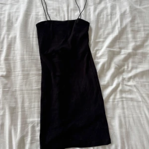 Svart kort klänning med tunna band - Från pull and bear. Storlek XS. Enkel och stilren svart kortklänning med tunna axelband. Klänningen har en rak passform och är perfekt för dig som gillar minimalistisk stil. Passar lika bra till sneakers som till klackar.