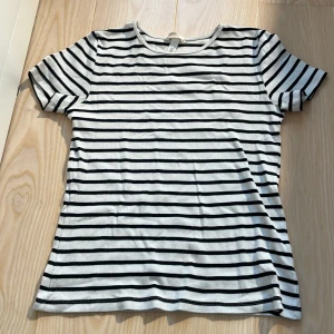 Randig t-shirt från H&amp;M, vit och svart - Säljer en klassisk vit t-shirt med svarta ränder från H&amp;M