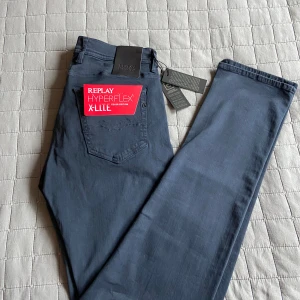 Replay Hyperflex X-Lite jeans blå - Snygga och helt nya Replay Hyperflex X-Lite jeans i mörkblå färg. Modellen har klassisk femficksdesign, stretchigt material och svart Replay-läderpatch bak. Perfekta för dig som vill ha bekväma och stilrena jeans med modern passform.