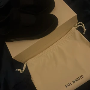 Svarta sneakers från Axel Arigato - Stilrena svarta sneakers från Axel Arigato med minimalistisk design. Skorna har en låg siluett och är tillverkade i skinn med platt sula. Perfekta för dig som gillar en clean och modern look.
