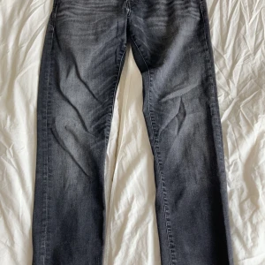 Svarta jeans från Jack & Jones, 31/32 - Klassiska svarta jeans från Jack & Jones – ett måste i garderoben! Jeansen har en stilren och tidlös design som passar till allt, oavsett om du klär dig upp eller ner. Bekväm passform med lätt stretch för extra rörelsefrihet.  🖤 Färg: Djupsvart 👖 Modell: Slim Stretch 📏 Storlek: W/31 L/32 🧵 Material: Bomullsblandning med stretch 📦 Skick: Använda 2 gånger, inga hål eller fläckar  Perfekta både till vardags och fest. Ett säkert kort för dig som gillar enkel och snygg stil.