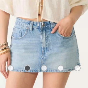 Ljusblå jeanskjol  - Säljer en ljusblå jeanskjol från Monki med klassisk femficksmodell, hög midja och rå, fransig kant nertill. Kjolen är kort och har bälteshällor samt dragkedja och knapp framtill. Perfekt för en chill och trendig look i sommar.