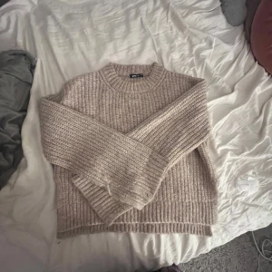 Beige stickad tröja från Gina Tricot - Supermysig beige stickad tröja från Gina Tricot i grovstickat material. Tröjan har rund halsringning, långa ärmar och breda ribbade muddar vid ärmslut och nederkant. Perfekt för lager-på-lager och chill höst- och vinterstil.