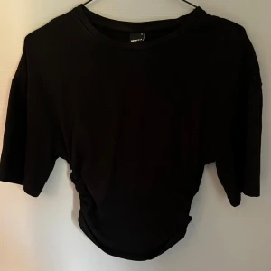 Svart croppad topp från Gina Tricot - Populär svart croppad topp från Gina Tricot med korta ärmar och rund halsringning. Är använd ett fåtal gånger och är i mycket bra skick.