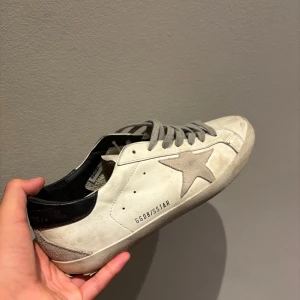 Golden goose - Golden Goose Superstar herr EU 41 (passar som 42) Välanvänd men mycket väl omhändertagen modell i äkta GG‑stil. Sulorna visar tydligt slitage, men läder, sömmar och insida är i gott skick — inga sprickor, fläckar eller missfärgningar. Designens ”distressed” look är trevligt rundad, inget överdrivet slitet. Inte super bra skick i sulan men resten är mycket bra!