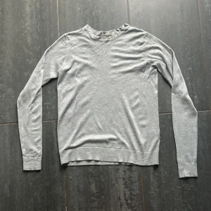 Ljusgrå basic tröja från Basic You - En stilren ljusgrå långärmad tröja från Basic You. Tröjan har rund halsringning och är tillverkad i mjuk bomull, perfekt för lager-på-lager eller som den är. 