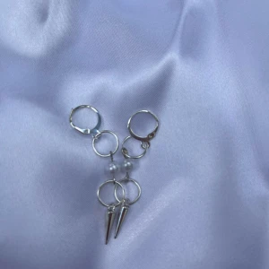 Silvriga örhängen med pärlor och spikes - Unika silvriga örhängen med små ringar, vita pärlor och coola konformade spikes. Ger en edgy vibe och passar perfekt för dig som vill sticka ut. Snyggt att matcha med andra silversmycken.