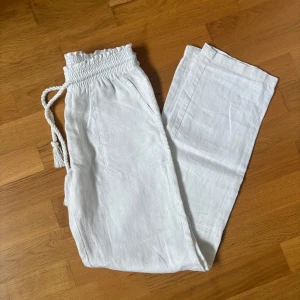 Vita linnebyxor - Snygga vita linnebyxor med bred resår i midjan och snörning framtill. Byxorna har låg midja och raka ben. Perfekta under varma dagar