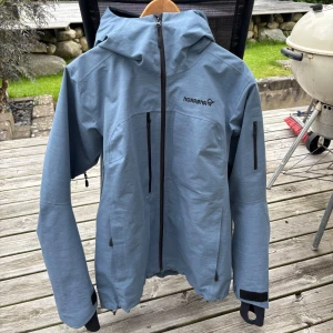 Blå skaljacka från Norrøna - Säljer nu min skaljacka från Norröna i storlek L (dam). Modellen Røldal, Gore-Tex. Funkar till skidåkning och massa andra aktiviteter då den stöter bort både vind och vatten. Lite tjockare skal än många andra som är väldigt tunna skal. Ventilation finns under båda armarna och den har både bröstfickor och en ficka på ena armen. Små defekter på luvan (se sista bilden). Pris går att diskutera. Skriv för frågor eller fler bilder! 