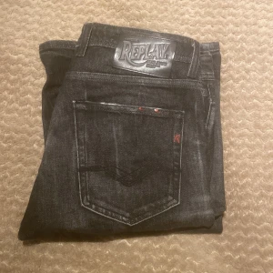 Svarta jeans från Replay - Snygga svarta jeans från Replay med en cool sliten look. De har en klassisk femficksdesign och knappar i gylfen. Perfekta för en avslappnad stil.