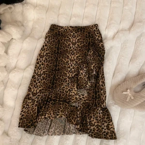 Leopardmönstrad kjol från NA-KD - Snygg leopardmönstrad kjol från NA-KD med volangdetaljer. Kjolen har en omlott-design som ger en trendig look. Perfekt för att sticka ut med ett djärvt mönster💓