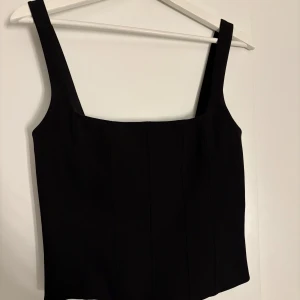 Oanvänd svart korsettopp från Zara - Snygg svart korsettopp från Zara med breda axelband och dragkedja i ryggen. Perfekt för en stilren look.💞 Köpt för 349 hos Zara! Aldrig använd bara testad!