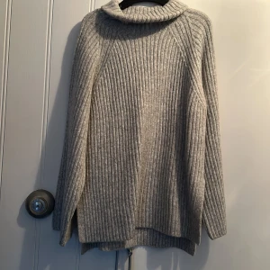 Grå ribbad polotröja från Gina Tricot - Säljer en mysig grå ribbad polotröja från Gina Tricot. Tröjan har långa ärmar och en bekväm passform, perfekt för kyliga dagar. Den är tillverkad i ett mjukt material som håller dig varm och stilren.