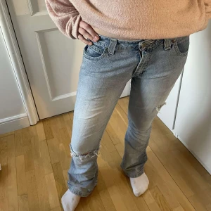 Blå jeans med slitningar - Jättesnygga ljusblå lågmidjade bootcut jeans med slitningar på knäna. Perfekta för en avslappnad look. Jag har sytt om dem eftersom de var för stora när jag köpte dem. Midjemåttet är 81 cm och innerbenslängden 76 cm.💕