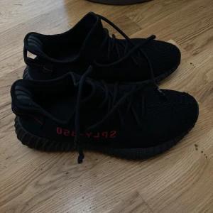 yeezy 350 v2 black and red - Yeezy 350 v2 boost  med röd text på sidan. Skorna har en stickad ovandel och snörning för en bekväm passform. Yttersulan är designad för bra grepp och komfort.