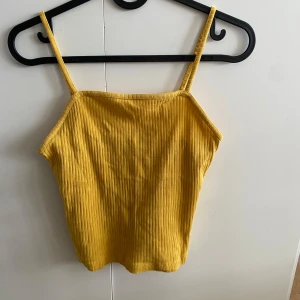 Gul ribbad linnetopp från Bik Bok - Säljer en snygg gul ribbad linnetopp från Bik Bok. Toppen har smala axelband och en enkel design som passar perfekt för sommardagar. Den passar inte längre, därför jag säljer denna:)