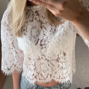 Vit spetsblus - Säljer en söt vit spetsblus med korta ärmar och blommigt mönster. Blusen är croppad och passar perfekt nu till våren och sommaren.