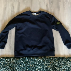  Stone Island tröja - Mörkblå tröja från Stone Island med deras ikoniska märke på ärmen.Perfekt för en avslappnad och trendig look. Säljer den eftersom den är för stor på bredden. Batchen är lite skadad eftersom jag råka tvätta den. Helt oanvänd. Passar M eftersom den är större på bredden