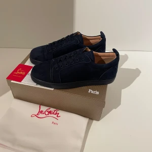 Mörkblå Loubs  - Snygga mörkblå sneakers i mocka från Christian Louboutin. Skorna har en stilren design med den trendiga röda sulan. Kom gärna med prisförslag.