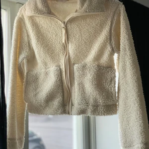 Vit teddyjacka med dragkedja - Mysig vit teddyjacka med dragkedja framtill och två stora fickor. Strl XS, liten i storleken.