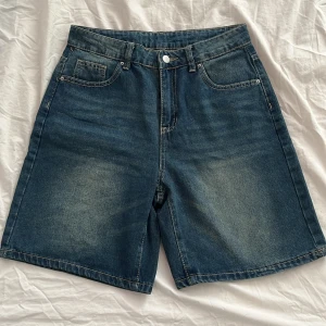 Jeansshorts från SHEIN  - Snygga jeansshorts från SHEIN i en klassisk blå färg. De har en normal passform med fem fickor och knappstängning. Perfekta för en avslappnad stil.