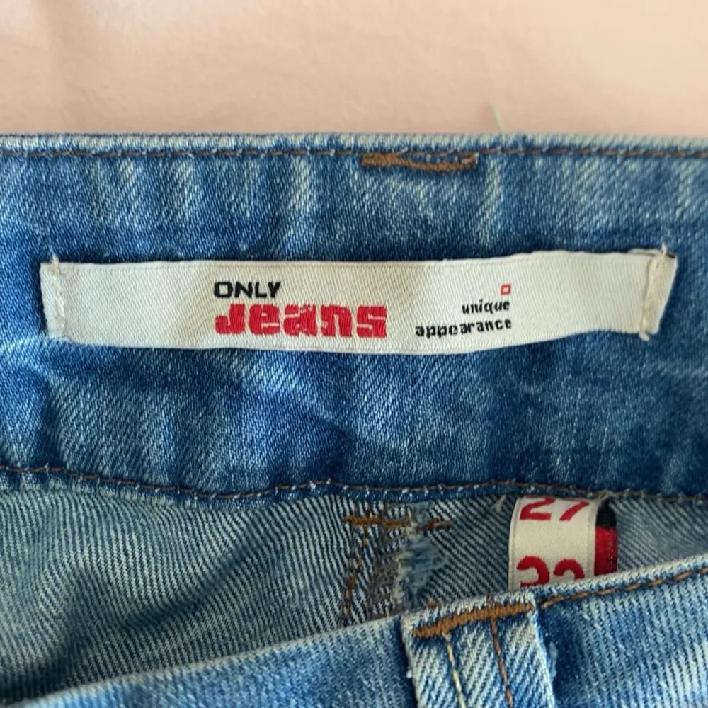 Snygga blå jeans från only med en klassisk femficksdesign och slitna detaljer. De har en knappgylf och en läderpatch baktill i midjan. Utsvängda och lågmidjade. Midjemått 40, innerbens 73💕. Farkut & Housut.