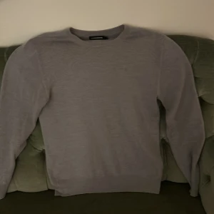 Grå tröja från J.Lindeberg - Säljer en stilren grå tröja från J.Lindeberg. Tröjan har en klassisk design med rund hals och långa ärmar. Perfekt för en avslappnad men ändå elegant look.