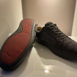 Christian Louboutin - Köpe för 6800kr Snygga svarta sneakers i mocka kommer me box och dust bag med en unik röd sula. Skorna har klassisk snörning och en stilren design som passar perfekt för vardagsbruk. Säg till om ni har frågor.