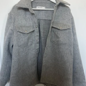 Grå jacka från Carin Wester - Säljer min mammas grå jacka från Carin Wester. Jackan har långa ärmar och två bröstfickor med knappar. Enkel att matcha med olika outfits och är i stolek 40.