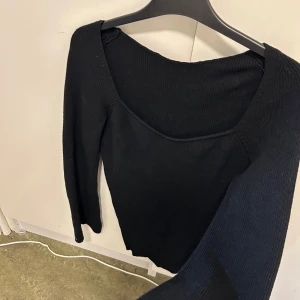 Svart ribbad tröja - Snygg svart ribbad tröja med lång ärm och en stilren design. Perfekt för en minimalistisk look. Tröjan har en bekväm passform och är ett mångsidigt tillskott till garderoben.