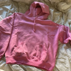Rosa hoodie - Säljer en mysig rosa hoodie med ficka fram och justerbar huva. Den har ribbade muddar vid ärmslut och nederkant. Från bikbok💕 knappt använd men har ett pyttehål fram som syns på sista bilden💕 annars i nyskick