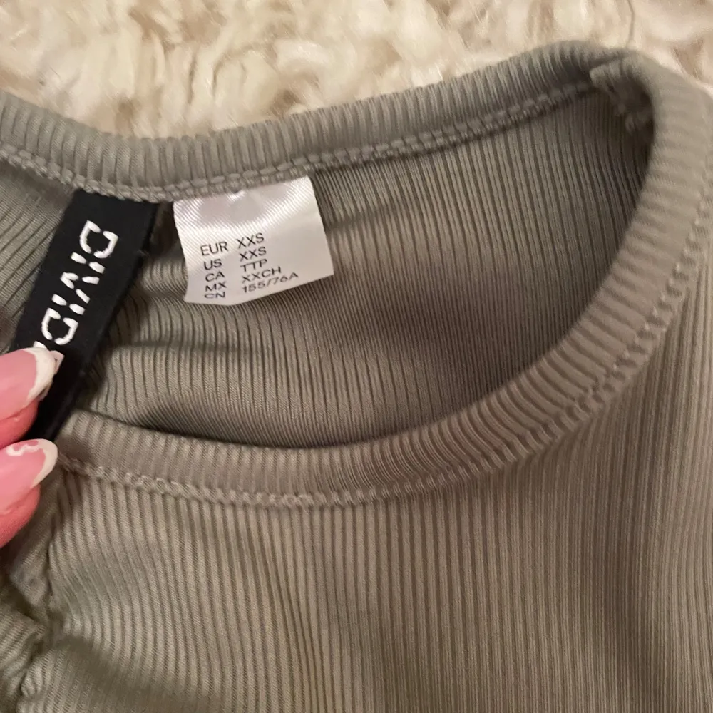 Snygg grön ribbad klänning från H&M Divided med korta ärmar och en åtsittande passform. Klänningen har en rynkad detalj längs framsidan, sidorna och i bak som ger en cool look. Är väldigt tight och ganska liten i storleken. Ganska använd men inga märken på det. Kan sänka pris. Mekot.