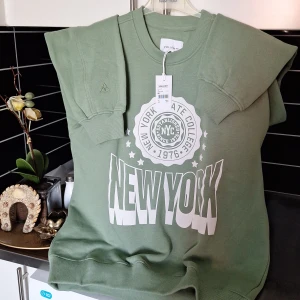 Grön sweatshirt från Vailent - Säljer en grön sweatshirt från Vailent med trycket 'New York' i vitt på framsidan. Tröjan har rund hals och långa ärmar med ribbade muddar. Perfekt för en avslappnad stil.