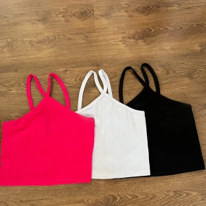 Tre ribbade linnen i olika färger - Säljer nu tre stycken ribbade linnen med korsade axelband. Ljusblå, rosa och svart. Alla för 110kr tillsammans. Från Gina Tricot. Storlek XL men passar också L. Defekt på det rosa linnet men går bort i tvätten. Passar perfekt nu till sommaren☀️💗