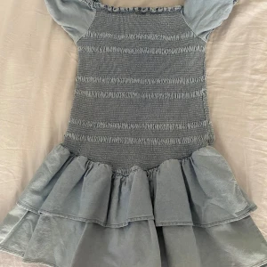Blå volangklänning från Seed Teen💙 - Supersöt ljusblå klänning från Seed Teen med smockad överdel och volangig kjol. Offshoulder-modell med korta puffärmar och rynkade detaljer upptill. Helt oanvänd med prislappen på.