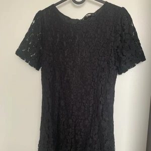 Svart spetsklänning från Bik Bok - Supersnygg svart kortklänning från Bik Bok med spets över hela klänningen. Den har korta ärmar, rund halsringning och dragkedja bak. Perfekt för dig som gillar en klassisk men ändå trendig look.