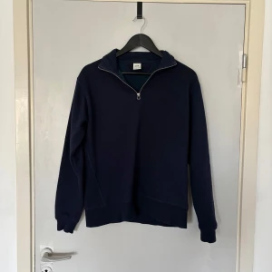 Mörkblå half zip tröja från Zara - Mörkblå sweatshirt från Zara med half zip-dragkedja och hög krage. Tröjan har långärmad passform och är gjord i mjuk bomull, perfekt för lager-på-lager. Enkel och stilren design som funkar till det mesta.