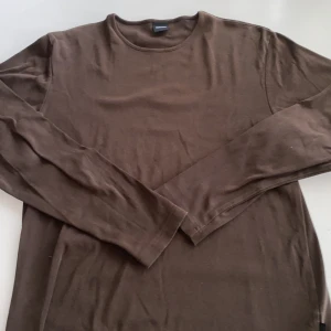 Brun långärmad tröja från BOSS - Snygg brun långärmad tröja från BOSS med rund halsringning. Tröjan är i mjuk bomull och har en clean, enkel design utan mönster eller detaljer. Perfekt för dig som gillar stilrena basplagg med premiumkänsla.