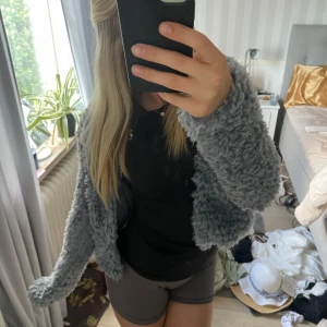 Grå/blå fluffig pälsjacka - Säljer en supermjuk och fluffig grå/blå pälsjacka med krullig struktur. Jackan är kortare i modellen och har en oversized passform som ger en cool och avslappnad vibe. Perfekt att slänga över en hoodie eller t-shirt. Är i storlek XS och kommer från H&M. Har aldrig använts och har prislappen kvar. 