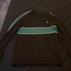 Svart tröja med grön rand Lyle & Scott - Svart långärmad tröja från Lyle & Scott i storlek M