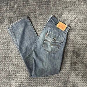Levis jeans i blå denim - Säljer ett par klassiska Levis jeans 514.I storlek W29 L32. De har en straight passform med lite bootcut. De knappar på bakfickorna och snygga detaljer . Perfekta för en avslappnad stil. Finns en fläck under vänstra bakfickan 