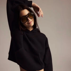 Svart croppad hoodie med huva - Svart  hoodie med huva och långa ärmar. Tröjan har en avslappnad passform och är perfekt för en chill och trendig look. Klassisk känguruficka framtill och mjukt material som känns skönt mot huden.