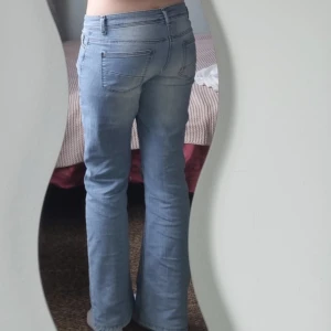 Ljusblå bootcut jeans låg midja - Säljer ett par ljusblå jeans med bootcut-modell och låg midja. Jeansen har klassiska fickor fram och bak, och är tillverkade i mjukt denimtyg. Perfekta för dig som gillar en avslappnad och trendig look.