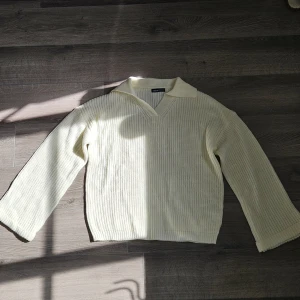 Krämvit stickad tröja från SHEIN - Krämvit stickad tröja från SHEIN med bred krage och v-ringning. Tröjan har långa ärmar och en ribbad struktur som ger en chill och trendig vibe. Perfekt att styla med jeans eller kjol för en snygg look. Säljer denna för att den inte kommer till användning 